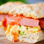 Cut open Spam, scrambled egg and spring onion sandwich with sweet chilli sauce .