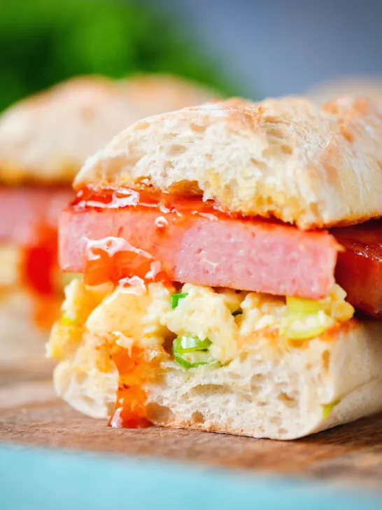 Cut open Spam, scrambled egg and spring onion sandwich with sweet chilli sauce .