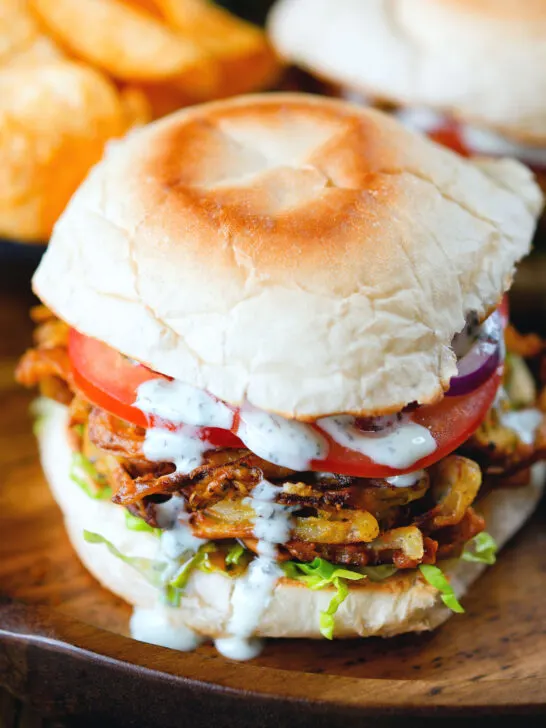 Bhaji burger or butty with lettuce, tomato, red onion and a mint raita sauce.
