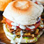 Bhaji burger or butty with lettuce, tomato, red onion and a mint raita sauce.