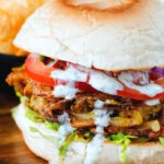 Bhaji burger or butty with lettuce, tomato, red onion and a mint raita style sauce.