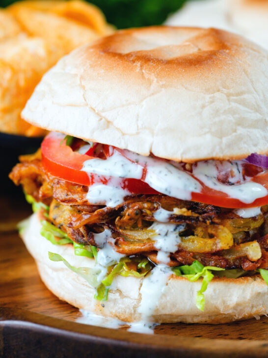 Bhaji burger or butty with lettuce, tomato, red onion and a mint raita style sauce.