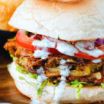 Bhaji burger or butty with lettuce, tomato, red onion and a mint raita style sauce.