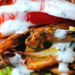 Close-up bhaji burger or butty with lettuce, tomato, red onion and a mint raita style sauce.