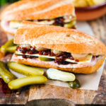 Ploughman's lunch sandwich with ham cheese and pickles on a crusty baguette.