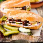 Ploughman's lunch sandwich with ham cheese and pickles on a crusty baguette.