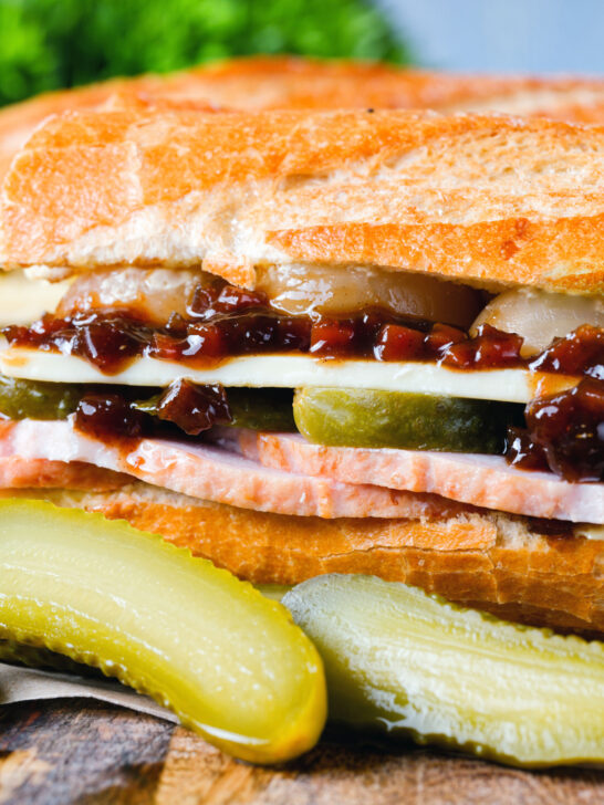 Close-up ploughman's lunch sandwich with ham cheese and pickles on a crusty baguette.