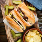 Overhead ploughman's lunch sandwich with ham cheese and pickles on a crusty baguette.