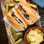 Overhead ploughman's lunch sandwich with ham cheese and pickles on a crusty baguette.