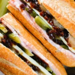 Overhead close-up ploughman's lunch sandwich with ham cheese and pickles on a crusty baguette.