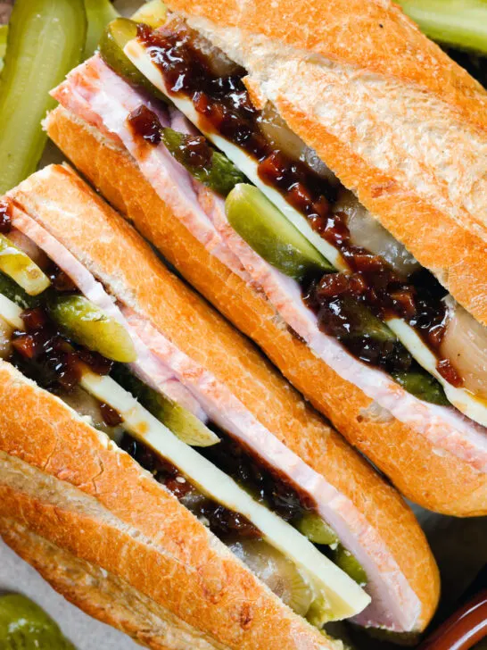 Overhead close-up ploughman's lunch sandwich with ham cheese and pickles on a crusty baguette.