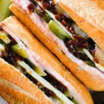 Overhead close-up ploughman's lunch sandwich with ham cheese and pickles on a crusty baguette.
