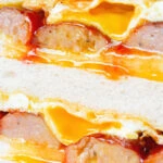 Close-up sausage and egg butty on thick sliced white bread.