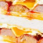 Close-up sausage and egg butty on thick sliced white bread.