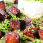 Close-up crispy tofu Thai green curry with fresh herbs and jasmine rice.