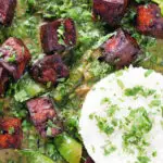 Overhead close-up crispy tofu Thai green curry with fresh herbs and jasmine rice.