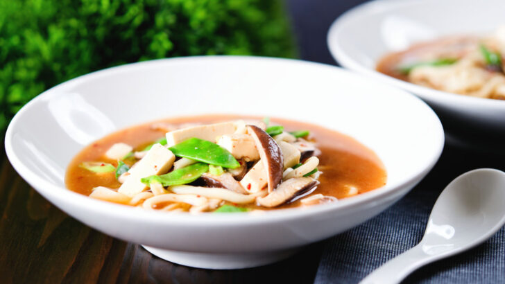 Spicy vegan miso noodle soup with silken tofu, mangetout and shiitake mushrooms.