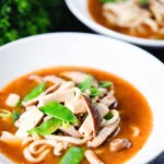 Two bowls of vegan miso noodle soup with tofu, mangetout and shiitake mushrooms.