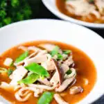 Two bowls of vegan miso noodle soup with tofu, mangetout and shiitake mushrooms.