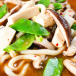 Close-up vegan miso noodle soup with tofu, mangetout and shiitake mushrooms.