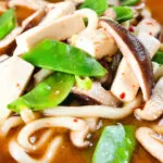 Close-up vegan miso noodle soup with tofu, mangetout and shiitake mushrooms.