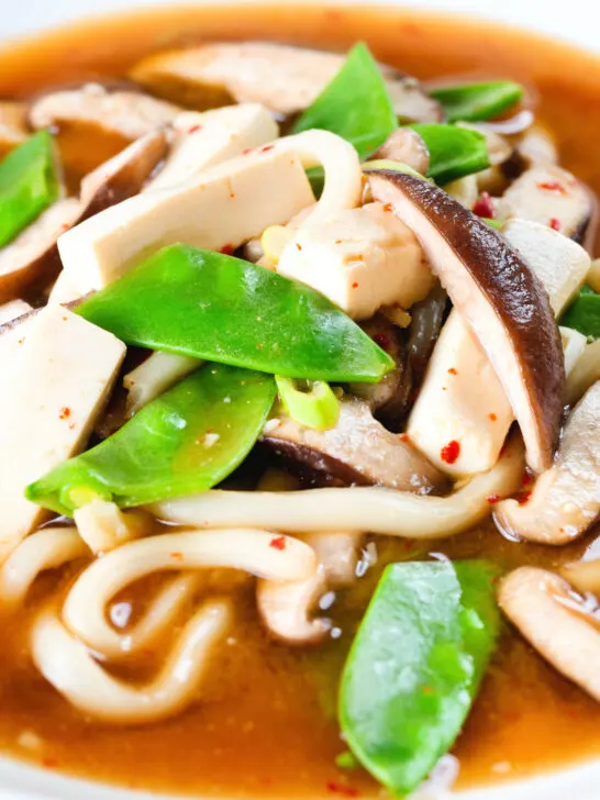 Close-up vegan miso noodle soup with tofu, mangetout and shiitake mushrooms.
