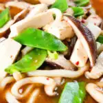 Close-up vegan miso noodle soup with tofu, mangetout and shiitake mushrooms.