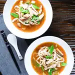 Two bowls (overhead) of vegan miso noodle soup with tofu, mangetout and shiitake mushrooms.