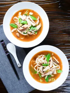 Two bowls (overhead) of vegan miso noodle soup with tofu, mangetout and shiitake mushrooms.