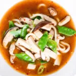 Overhead close-up vegan miso noodle soup with tofu, mangetout and shiitake mushrooms.