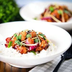 Vegan bang bang cauliflower with red onion and ginger served with white rice.