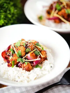 Spicy fried bang bang cauliflower garnished with ginger and coriander served with white rice.