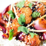 Close-up bang bang cauliflower garnished with ginger and coriander served with white rice.