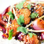 Close-up bang bang cauliflower garnished with ginger and coriander served with white rice.