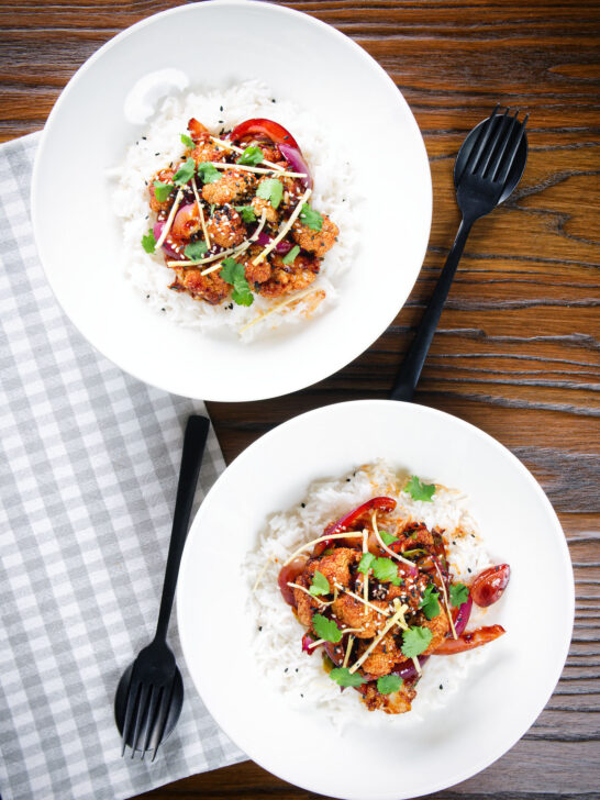 Overhead bang bang cauliflower garnished with ginger and coriander served with white rice.