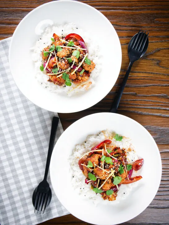 Overhead bang bang cauliflower garnished with ginger and coriander served with white rice.