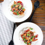 Overhead bang bang cauliflower garnished with ginger and coriander served with white rice.