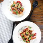 Overhead bang bang cauliflower garnished with ginger and coriander served with white rice.