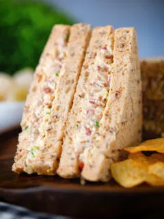 Close-up cheese and onion sandwich with Branston pickle on malted bread served with crisps.