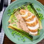 Overhead chicken breast in a creamy cider mustard sauce served with baby leeks and peas.