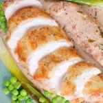 Overhead close-up chicken breast in a creamy cider mustard sauce served with baby leeks and peas.