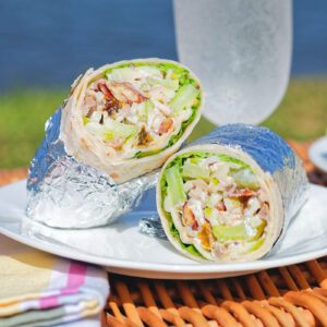Chicken Waldorf salad wraps in a flour tortilla served on a picnic basket.