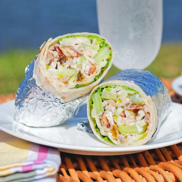 Chicken Waldorf salad wraps in a flour tortilla served on a picnic basket.