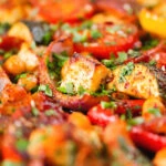 Close-up halloumi tray bake with Mediterranean vegetables, chickpeas and spicy harissa.