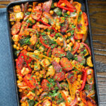 Overhead halloumi tray bake with Mediterranean vegetables, chickpeas and spicy harissa.