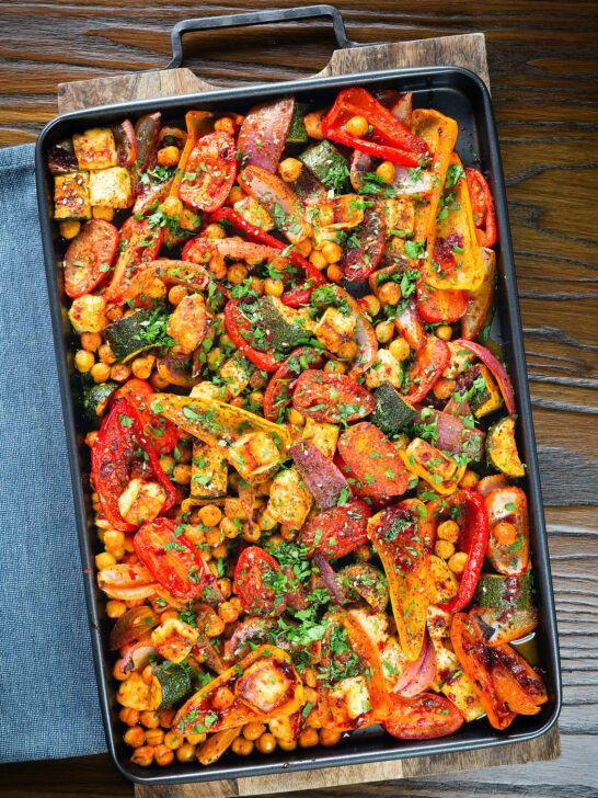 Overhead halloumi tray bake with Mediterranean vegetables, chickpeas and spicy harissa.