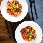 Halloumi cheese tray bake with Mediterranean vegetables, chickpeas and spicy harissa served in two bowls.