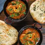 Overhead Indian takeaway inspired king prawn Balti curry with naan bread.
