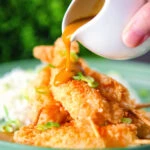 Homemade Japanese curry sauce being poured over king prawn katsu.