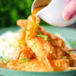 Homemade Japanese curry sauce being poured over king prawn katsu.